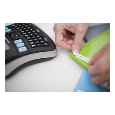 Dymo LabelManager 210D labelprinter i sort og sølv, hvor en hånd påsætter en label på en grøn mappe.