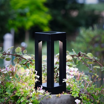 Eglo sort plast solcellelampe med spyd, 25,5 cm høj, placeret i blomsterbed med grønne planter.
