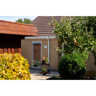 Plastmo nedløbsrør i hvidt PVC monteret på et hus, der leder vand væk fra et tegltag.