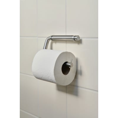 Nærbillede af Knud Holscher toiletrulleholder fra d line i børstet stål, der holder en toiletpapirrulle på en lys flisevæg.
