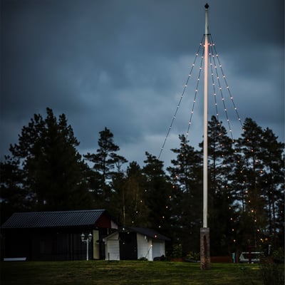 Konstsmide flagstangskæde monteret på flagstang ved skumringstid, skaber stemningsfuld belysning med 100 LED-lys.