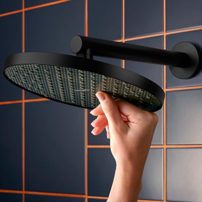 Hansgrohe Activera S hovedbruser i mat sort, vist med en hånd der berører den store 240mm stråleskive.