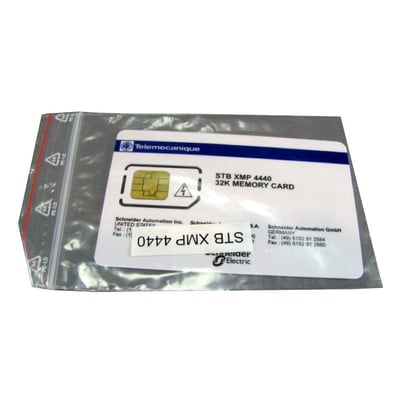 Nærbillede af Schneider Electric STB XMP 4440 32 KB memorykort, der viser chipdetaljer og mærkning, placeret i en plastiklomme.
