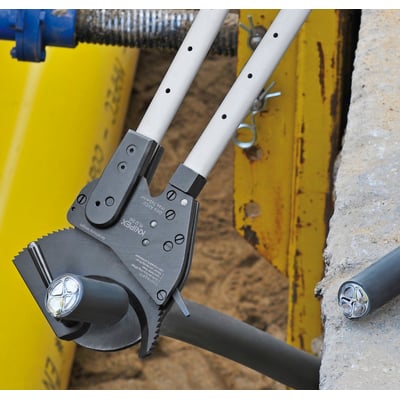 KNIPEX kabelsaks med teleskopskaft klippende i et tykt kabel, med synlige ledninger i det grå kabel.