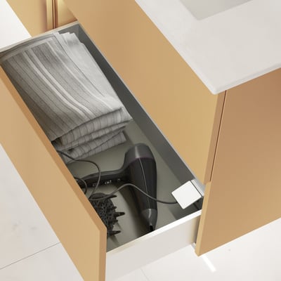 Dansani elstik i skuffe med en hårtørrer og håndklæder, monteret i et lys gyldent vaskeskab.