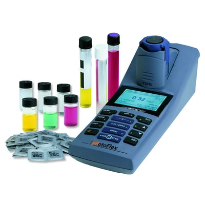 WTW PhotoFlex Turb, portabelt fotometer med pH- og turbiditetsmåler, vist med laboratorieglas og reagenspakker på hvid baggrund.