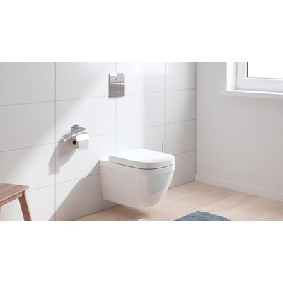 Grohe Solido Euro Ceramic hængetoilet i hvid med toiletsæde, monteret på en flisevæg ved siden af et vindue.