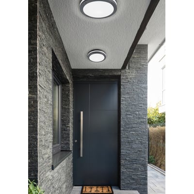 To Piave loftlamper med sensor fra TRIO Lighting monteret på en antracitsten beklædt facade ved en mørk hoveddør, ideel til udendørs belysning.