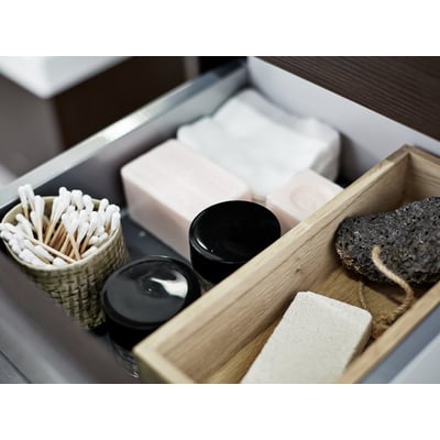 Dansani skuffeindsats i eg med vatpinde, sæber og pimpsten, viser praktisk opbevaring i et badeværelse.