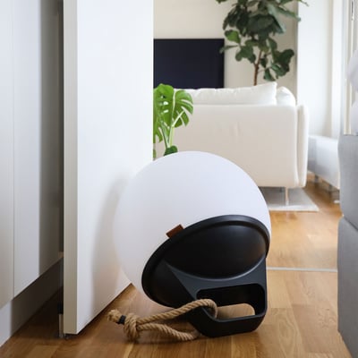 SACKit Light 350 udendørs batterilampe i plast og sort med rebdetalje, står på trægulv ved en døråbning.