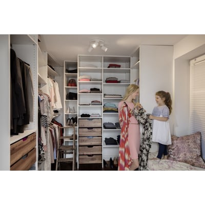 Mor og datter i et walk-in closet, omgivet af tøj og hylder med opbevaring.