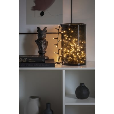 Konstsmide lyskæde med 200 varmhvide LED'er, pyntende en mørk glasvase med bobleeffekt.