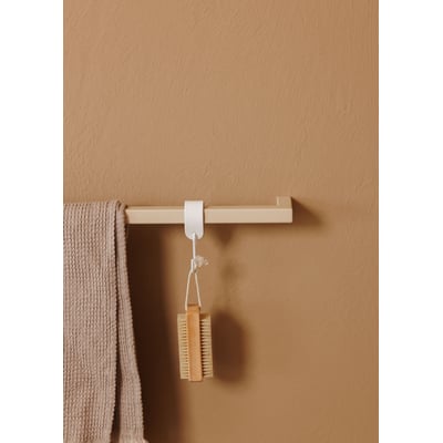 Metallbude Vana håndklædestang i beige, med et moderne firkantet design, hænger på en sandfarvet væg og har et håndklæde samt en børste hængende.