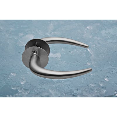 Assa Abloy Coupe-dørgreb i børstet rustfrit stål, vist skråt med slanke, buede greb og runde beslag.