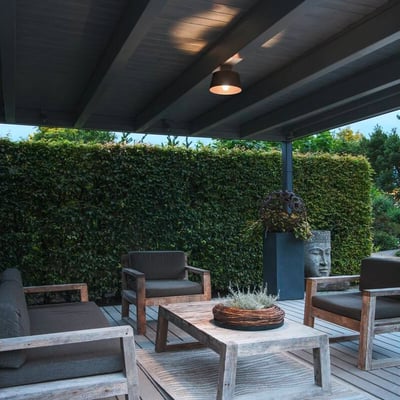 SLV PHOTONI loftlampe monteret på overdækket terrasse ved kystnære områder, belyser et udendørs siddeområde.