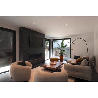 SLV One Bow FL standerlampe i sort stål, vist i et moderne loungeområde med sofaer og et stort vindue.