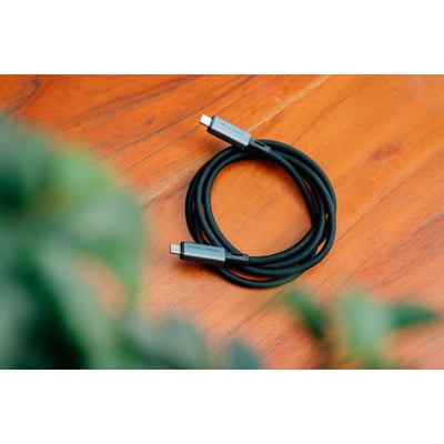 Sort Verbatim Sync & Charge USB-C-kabel, USB4 med 240 W opladning og 40 Gbit/s, ligger oprullet på et træbord.