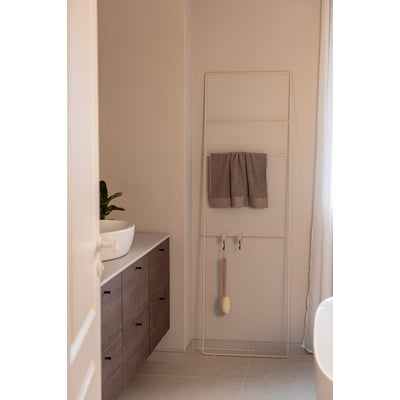 Metallbude Estina håndklædestige i beige, 1800mm høj, med et håndklæde hængende på den. Stigen står ved siden af et badeværelsesmøbel med vask.