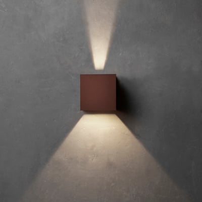 Lumenlight Toscana udendørs væglampe i corten monteret på en grå væg med lys kastet opad og nedad.