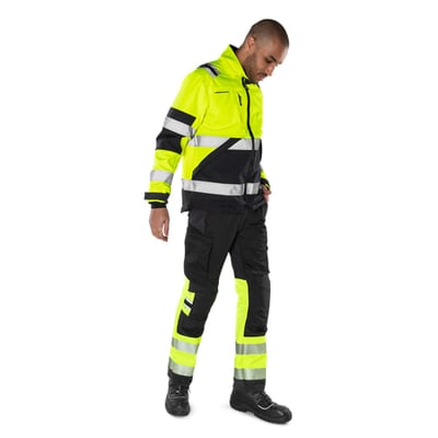Kansas Fristads Hi-Vis softshell jakke i gul og sort, str. S, båret af en mand, der viser moderne pasform og reflekterende detaljer.