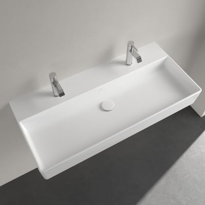 Villeroy & Boch Memento 2.0 håndvask, 100 cm, monteret på en hvid væg over et mørkegråt gulv, med to krom vandhaner og afløb.