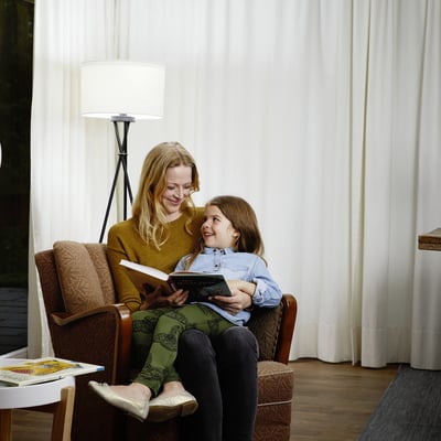 Ledvance LED standard Ra97 lyskilde monteret i en gulvlampe oplyser en kvinde og et barn, der læser sammen i en stue.