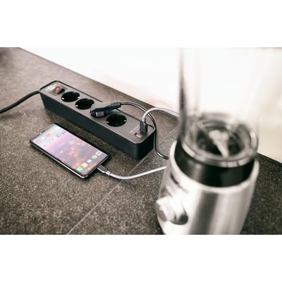 Brennenstuhl Ecolor forlængerledning i sort med fire stikkontakter og to USB-porte, forbundet til en smartphone og blender.