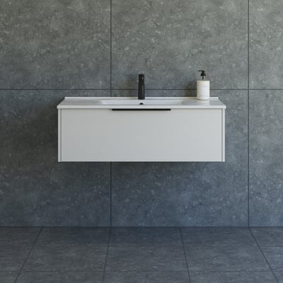 Dansani Mido+ Classic møbelpakke 101 cm bred, med en glat sandfarvet skuffefront og hvid vask, monteret på en grå flisevæg.