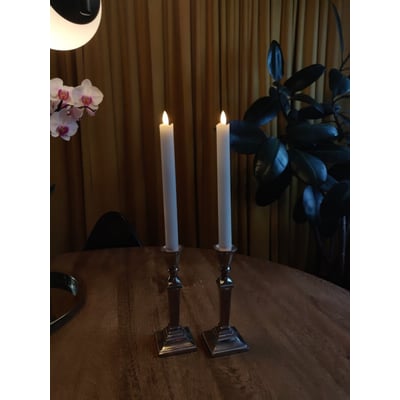 Nærbillede af et hvidt Veli Line 3D kronelys med bevægelig flamme, på en træoverflade.