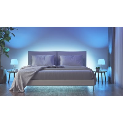 Nanoleaf Essentials Matter Smart Bulb E27 skaber stemningsfuld blå belysning i et soveværelse med dobbeltseng og sengeborde.