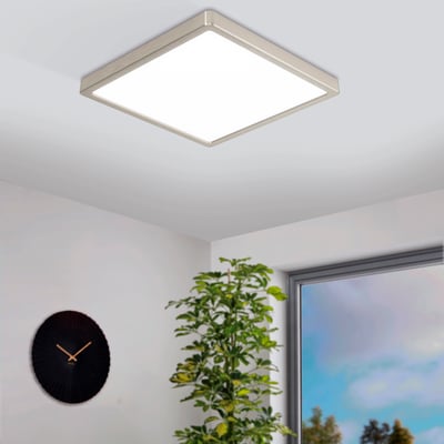 EGLO Fueva-Z loftlampe monteret på et lyst loft i et moderne rum med et ur og en grøn plante.