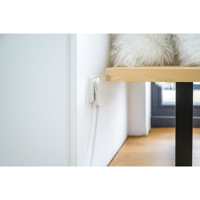 Hvid Brennenstuhl-forlængerledning på 2 meter med jordet, fladt vinkelstik og stikdåse, tilsluttet bag et bord.