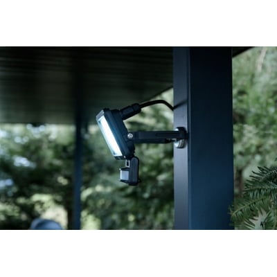 Brennenstuhl 20W LED projektør med sensor monteret på en mørkeblå stolpe, oplyser et udendørsområde.