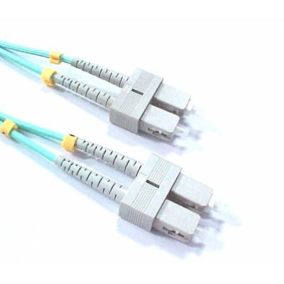 Fiberoptisk patchkabel med to SC/PC konnektorer i grå plast, med lyseblå kabel og gule manchetter, på hvid baggrund.