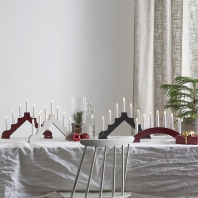 Star Trading Ada julelysestage i rød træ med 7 lys, placeret på et julepyntet bord.