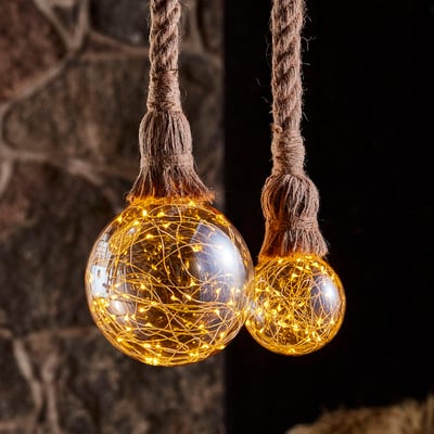 Nielsen Light Klokkeblomst globepære Ø95 mm med gyldent glas og indbygget LED lyskæde, hængende fra flettede snore.