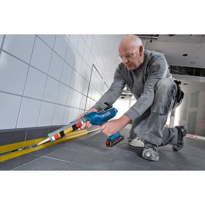 Bosch GCG 18V-310 batteridrevet fugepistol bruges til at lægge en fuge langs gulvfliser i et flisebelagt rum.