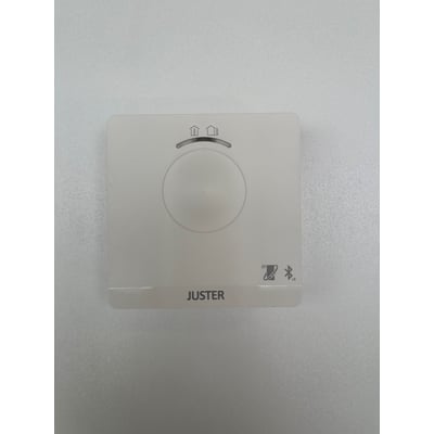 Hvid Juster Bluetooth TR3 enhed med symboler for bolig og Bluetooth, samt logoet 'JUSTER' på en grå, tekstureret baggrund.