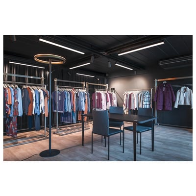 SLV One Straight FL standerlampe i sort og messing med en rund lyskilde, opstillet i et moderne butiksmiljø.