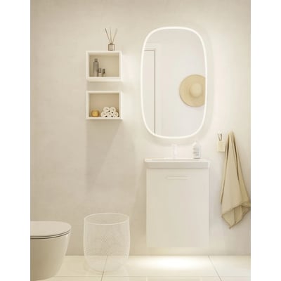 Dansani Squircle spejl, 100x60 cm, oval form med integreret frontlight. Viser spejlet monteret over et moderne hvidt badeværelsesmøbel med hygiejneartikler.