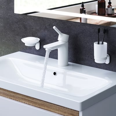 AM.PM X-Joy S et-grebs håndvaskarmatur i mat hvid funktionelt monteret på en hvid håndvask med rindende vand.