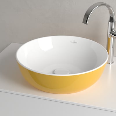 Detaljebillede af Villeroy & Boch Artis håndvask i gul BiColour med hvid inderside og et hvidt bundventil, set fra siden.