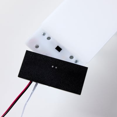 Nærbillede af bagsiden af et Loevschall Polaris Square LED lys, der viser tænd/sluk sensor og ledningsforbindelser.