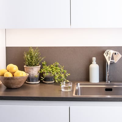 Markslöjd Combine skinne på 100 cm i hvid aluminium med integreret LED-lys, monteret over en køkkenbordplade.