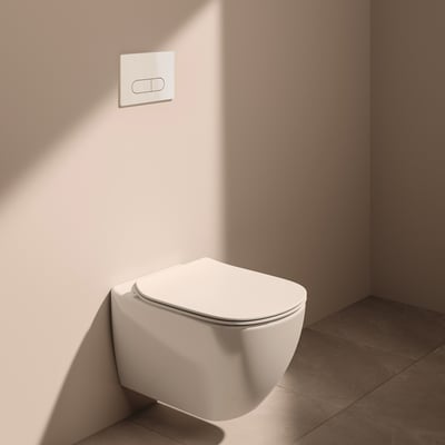 Ideal Standard væghængt toilet i hvid monteret på en lyserød væg, med lukket toiletsæde og skylleknap.