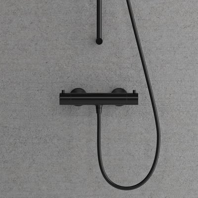 Nærbillede af Scandtap Steel Pleasure 1 Shadow termostatarmatur med 2-grebs betjening i matsort finish, monteret på betonvæg.