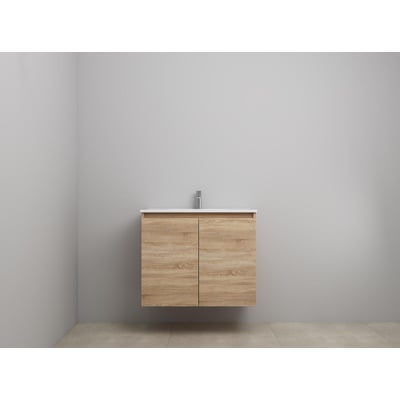 Sanibell Online møbelsæt i bardolino eg med to grebsfrie låger og en hvid porcelænsvask med armatur, monteret på en grå væg.