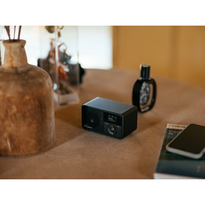 Sangean DDR-7X sort DAB+/FM-radio med trækabinet står på et bord med dekorationer.