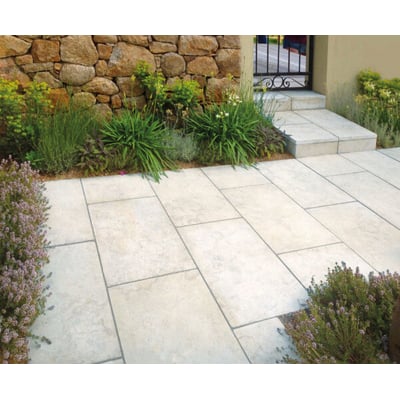 ECCO Products A-Joint Ready Flex belægningsfugemørtel i stone grey anvendt til fugning af lyse flisebelægninger med grønne planter og stenmur i baggrunden.