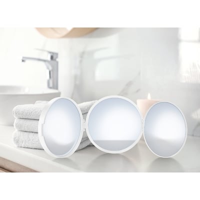 Smedbo outline lite rejsespejl i mat hvid, med tre runde spejloverflader, står på en bordplade ved siden af et foldet håndklæde og et stearinlys.